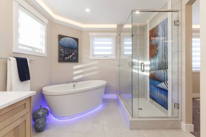 White tiled 5-piece bathroom with decorative shower.
Salle de bain blanche carrelée à cinq sanitaires comportant une douche décorative.