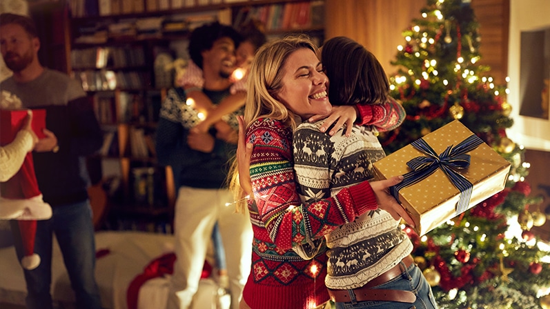 Two women hug over gift.
Deux femmes s'étreignent pour un cadeau.