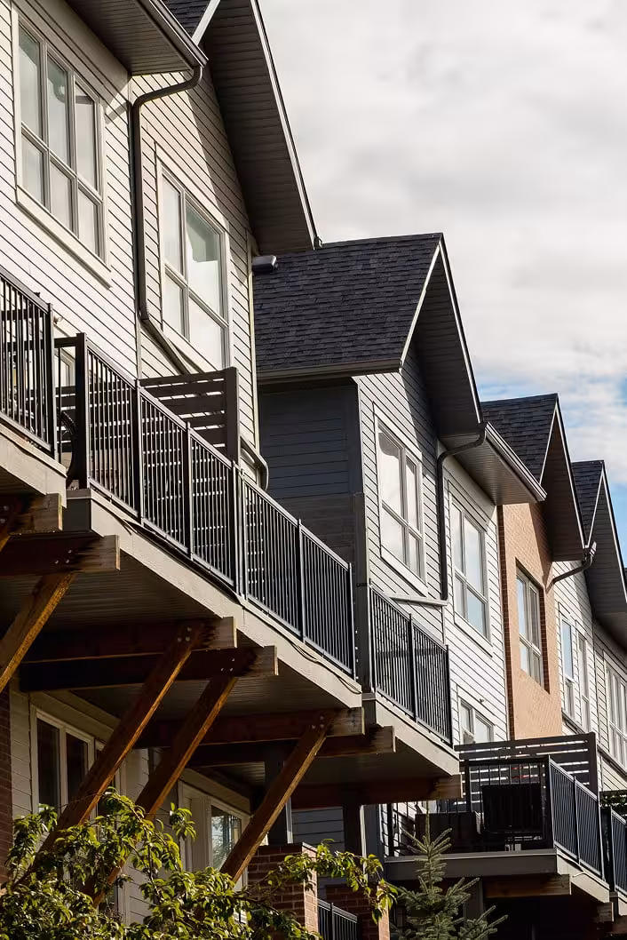 Close-up of multi-storey Griesbach homes with exterior balconies, black railings, and repeating peaked rooflines.